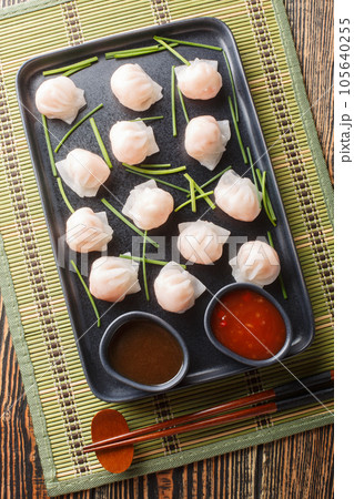 Traditional Asian Prawn or shrimp dumplings hakau, ha kauw or har gow served with sauce. Vertical top view 105640255