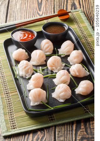 Chinese Har Gow Dim Sum dumplings in the shape of a bonnet served with sauce. Vertical 105640259
