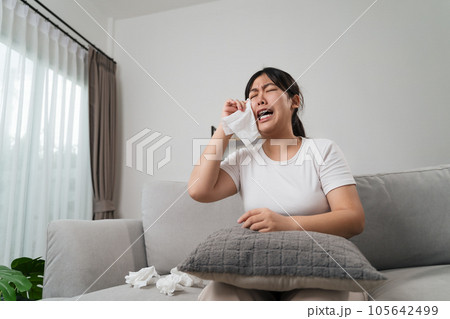 Portrait of a Sad Asian woman crying wipes her tears with a tissue paper towel. Portrait of a Sad Asian woman crying wipes her tears with a tissue paper towel. 105642499