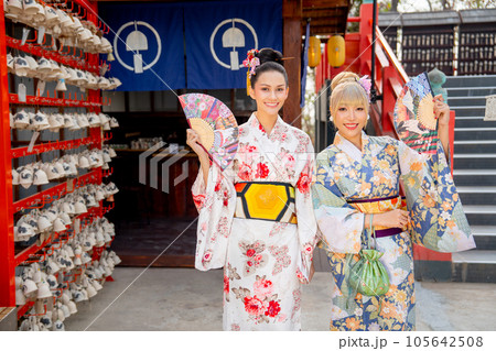Portrait of Asian women wear japanese style dress with hold multicolor fan and stand in front shop 105642508
