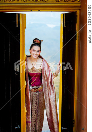 Beautiful Asian woman wear Thai traditional dress stand in area of ancient door of building temple 105642509