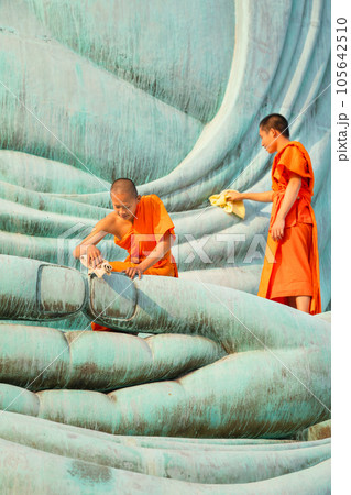 Vertical image of two young Asian monk stay with other monk on green big buddha statue to clean 105642510