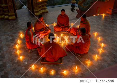 Close up group of young and senior monk sit in a circle with several lighting candle surround Close up group of young and senior monk sit in a circle with several lighting candle surround 105642596