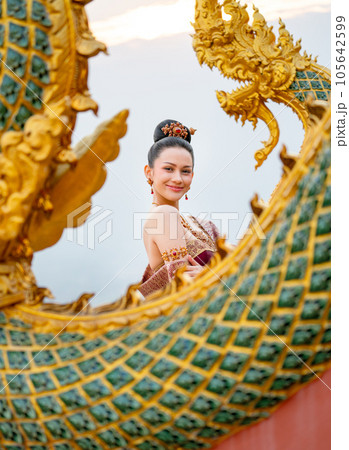 Portrait of beautiful Asian woman with Thai traditional dress stand behide the naga sculpture temple 105642599