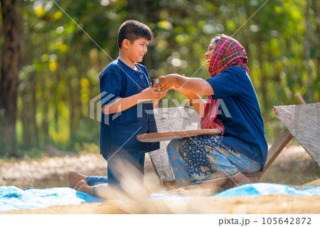 Asian boy bring drinking water and give to woman and she look happy during process of rice prepare 105642872