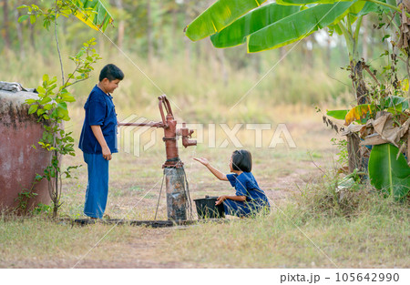 Asian boy use groundwater lever to get water for little girl and they look happy to get fresh water. Asian boy use groundwater lever to get water for little girl and they look happy to get fresh water. 105642990