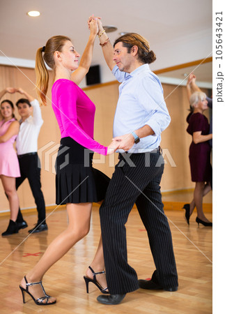 Cheerful man and woman practicing ballroom dances in ballroom 105643421