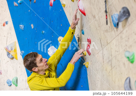 Young climber climbing indoor wall, sport concept Young climber climbing indoor wall, sport concept 105644199