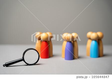 The concept of market segmentation. Target audience, customer care. Market group of buyers. Customer relationship management. Wooden figurines of people and magnifying glass 105644847