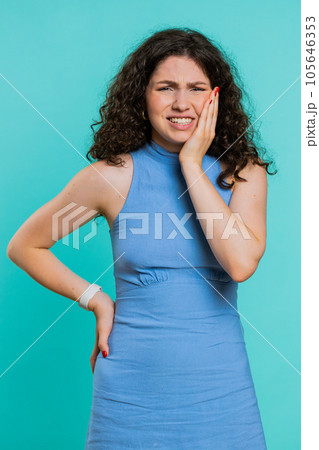 Young woman touching cheek, closing eyes with expression of terrible suffer from painful toothache 105646353