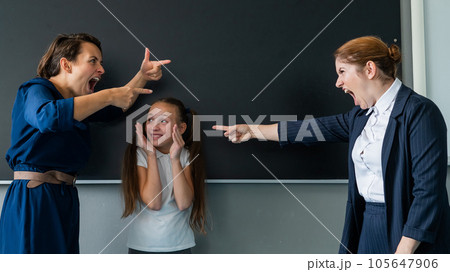 The female teacher screams at the schoolgirl and her mother standing at the blackboard. The female teacher screams at the schoolgirl and her mother standing at the blackboard. 105647906