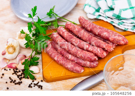 Raw pork longaniza ready for grilling on wooden board with condiments Raw pork longaniza ready for grilling on wooden board with condiments 105648256