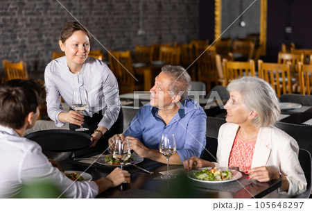 Waitress serving wine to guests of different ages in restaurant Waitress serving wine to guests of different ages in restaurant 105648297