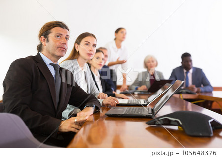 Middle aged white brunette businessman listening to presentation 105648376
