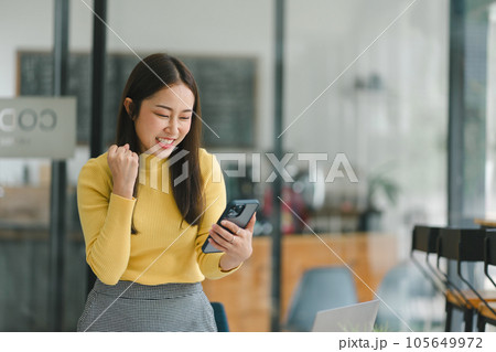 Portrait of a happy young businesswoman celebrating success with arms raised, fists clenched. The freelancer has finished a project. 105649972