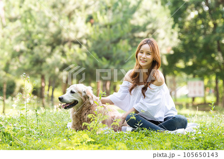 a happy young woman taking a walk with her dog in the park 105650143