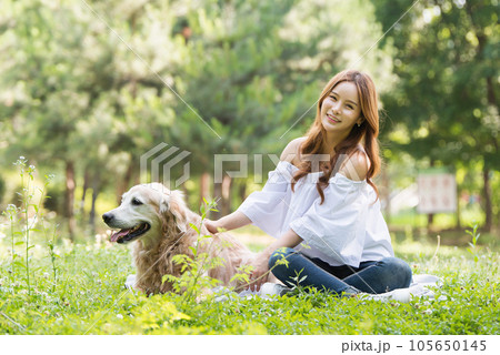 a happy young woman taking a walk with her dog in the park 105650145