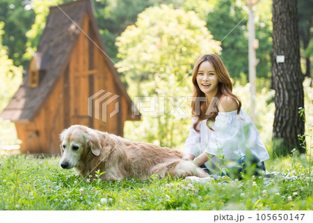 a happy young woman taking a walk with her dog in the park 105650147