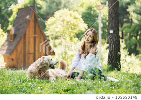 a happy young woman taking a walk with her dog in the park 105650149