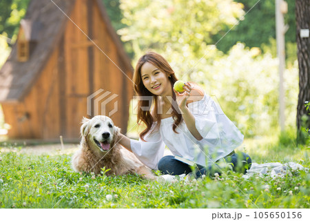 a happy young woman taking a walk with her dog in the park a happy young woman taking a walk with her dog in the park 105650156