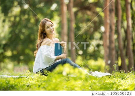 a beautiful young woman reading a book in the park 105650528