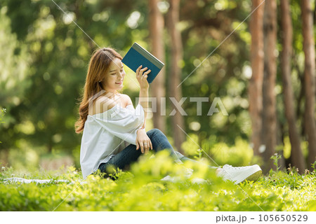 a beautiful young woman reading a book in the park a beautiful young woman reading a book in the park 105650529