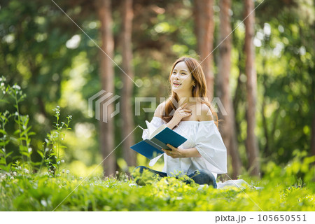 a beautiful young woman reading a book in the park 105650551