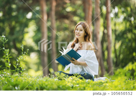 a beautiful young woman reading a book in the park 105650552