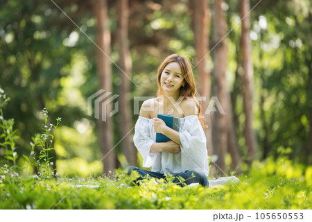 a beautiful young woman reading a book in the park 105650553
