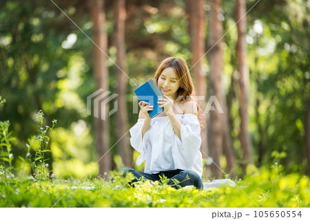 a beautiful young woman reading a book in the park 105650554