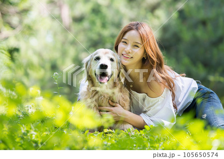 a happy young woman taking a walk with her dog in the park 105650574