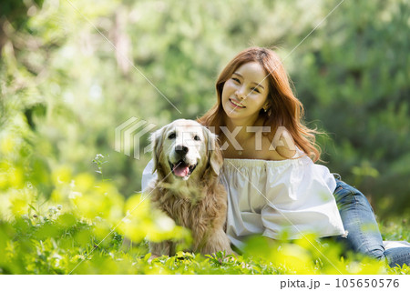 a happy young woman taking a walk with her dog in the park 105650576