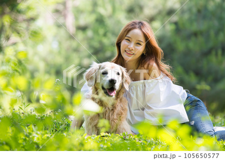 a happy young woman taking a walk with her dog in the park 105650577