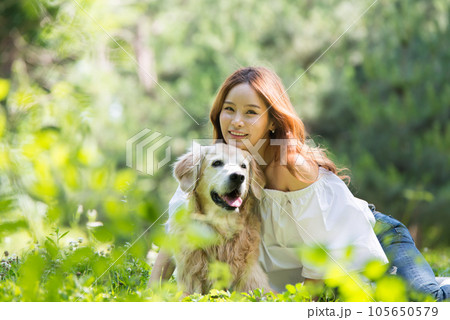 a happy young woman taking a walk with her dog in the park 105650579