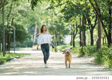 a happy young woman taking a walk with her dog in the park 105650581