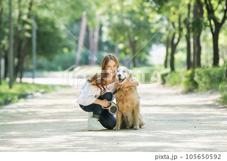 a happy young woman taking a walk with her dog in the park 105650592