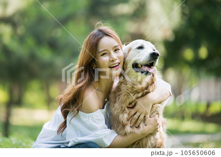 a happy young woman taking a walk with her dog in the park 105650606