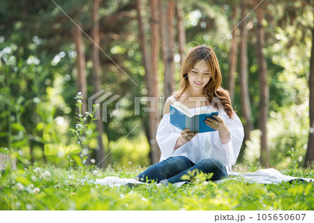 a beautiful young woman reading a book in the park a beautiful young woman reading a book in the park 105650607