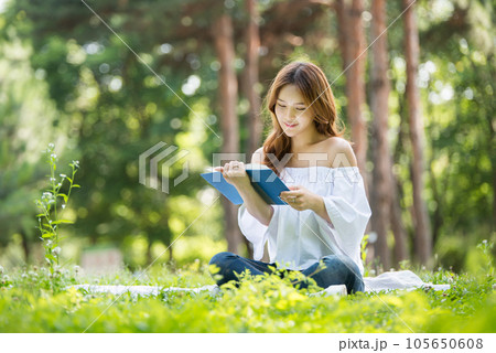 a beautiful young woman reading a book in the park 105650608