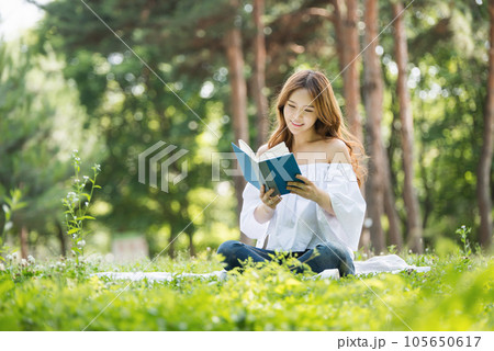 a beautiful young woman reading a book in the park 105650617
