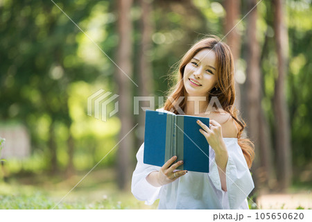 a beautiful young woman reading a book in the park a beautiful young woman reading a book in the park 105650620