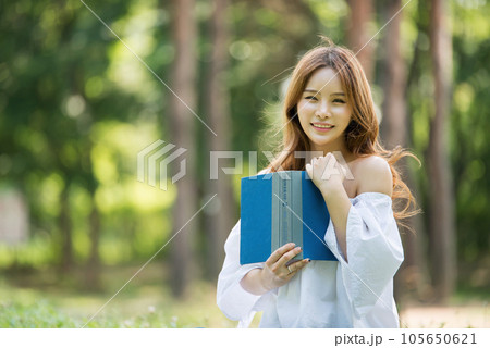 a beautiful young woman reading a book in the park a beautiful young woman reading a book in the park 105650621