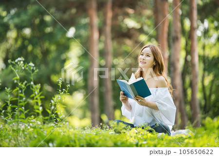 a beautiful young woman reading a book in the park a beautiful young woman reading a book in the park 105650622