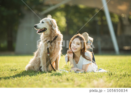 A beautiful young woman reading a book with her dog in the park A beautiful young woman reading a book with her dog in the park 105650834