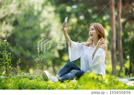 A beautiful young woman looking at her smartphone in the park A beautiful young woman looking at her smartphone in the park 105650856