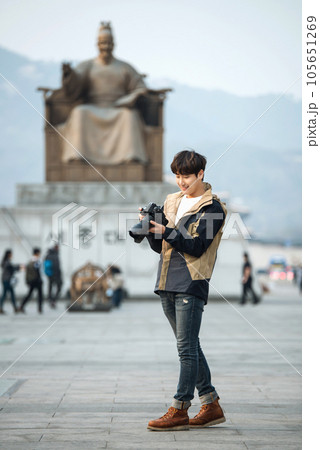 A young man holding a camera and taking pictures during a trip to Korea	 105651269