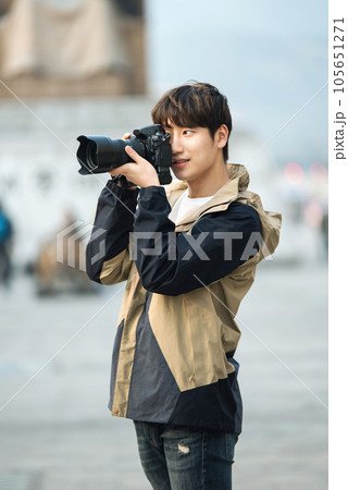 A young man holding a camera and taking pictures during a trip to Korea	 105651271