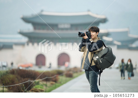 A young man holding a camera and taking pictures during a trip to Korea	 105651273