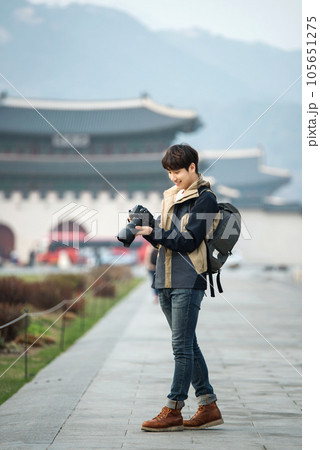 A young man holding a camera and taking pictures during a trip to Korea A young man holding a camera and taking pictures during a trip to Korea 105651275