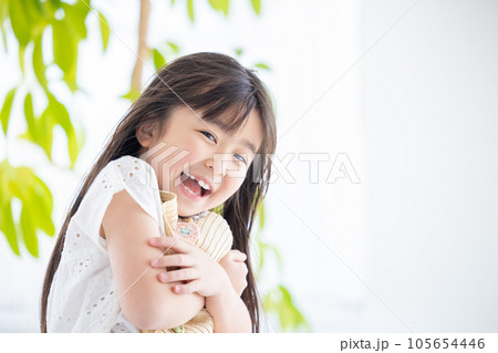 女の子のポートレート 風で飛ばされないように麦わら帽子をおさえる女の子 女の子のポートレート 風で飛ばされないように麦わら帽子をおさえる女の子 105654446